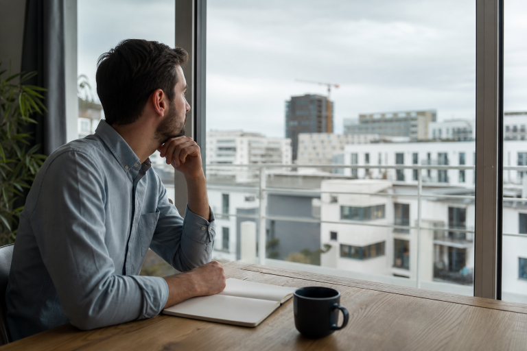 Homme pensif regardant la ville depuis un bureau